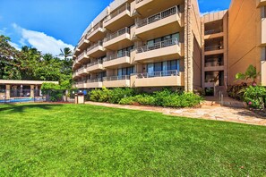 A multi-story hotel with balconies, a well-maintained lawn, and a stone pathway leading to the entrance. - Tropical Beach Oasis | Private Pool, Hot Tub & AC (Lahaina)