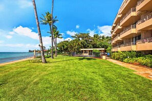 A beachfront hotel with a well-maintained lawn, palm trees, and a view of the ocean. - Tropical Beach Oasis | Private Pool, Hot Tub & AC (Lahaina)