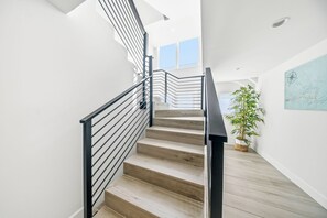 Escada com design moderno, destacando corrimão de metal e degraus de madeira.