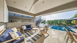 A poolside area with a sofa, chairs, and a staircase leading to an upper level. - Luxury Home +Carriage house | Waterfront| Pool 5bd (Marathon)
