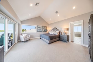 A bedroom with a large bed, a chair, a nightstand, and a window. - Luxury Home +Carriage house | Waterfront| Pool 5bd (Marathon)