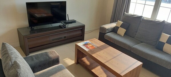Una sala de estar con sofá, una mesa de centro y un televisor sobre un mueble.