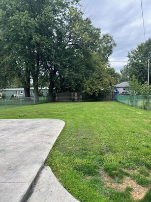 A grassy yard with a concrete path, trees, and a fence. - 3-bedroom lake house in Hamburg, 10 minutes from Bills Stadium! (Hamburg)