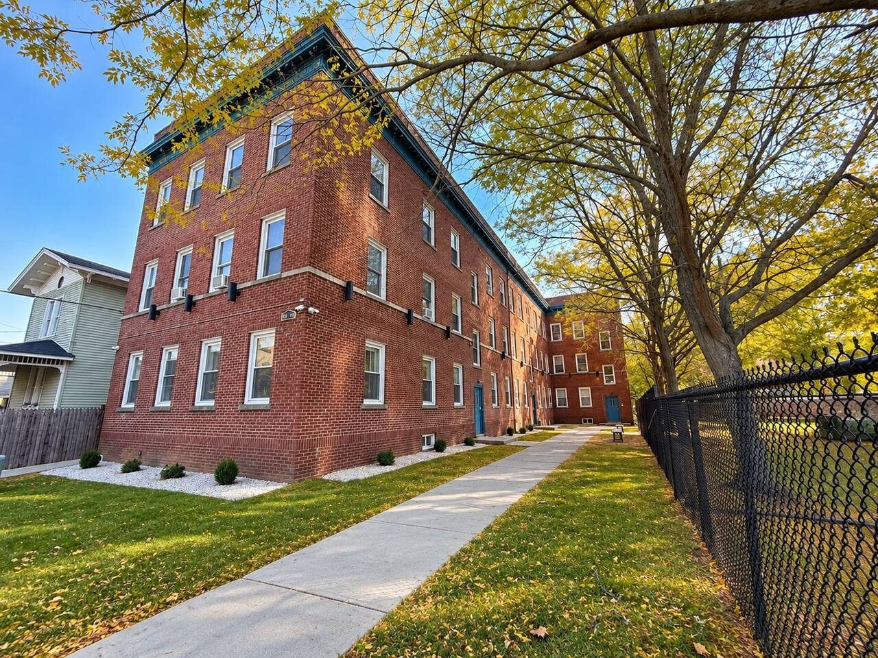 A multi-story brick building with a visible entrance and a pathway leading to it.