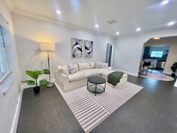 A modern living room with a sectional sofa, a round coffee table, and a floor lamp. - The Miami Urban House - Modern Serenity in the Heart of Miami (Miami)