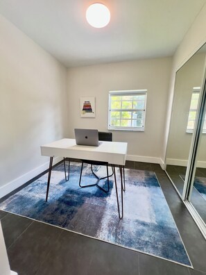 A room with a white desk, a laptop, a framed picture on the wall, a window, and a mirror. - The Miami Urban House - Modern Serenity in the Heart of Miami (Miami)