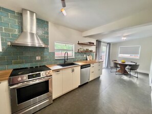 A modern kitchen with a stainless steel range, a dishwasher, and a window with a view of greenery. - The Miami Urban House - Modern Serenity in the Heart of Miami (Miami)