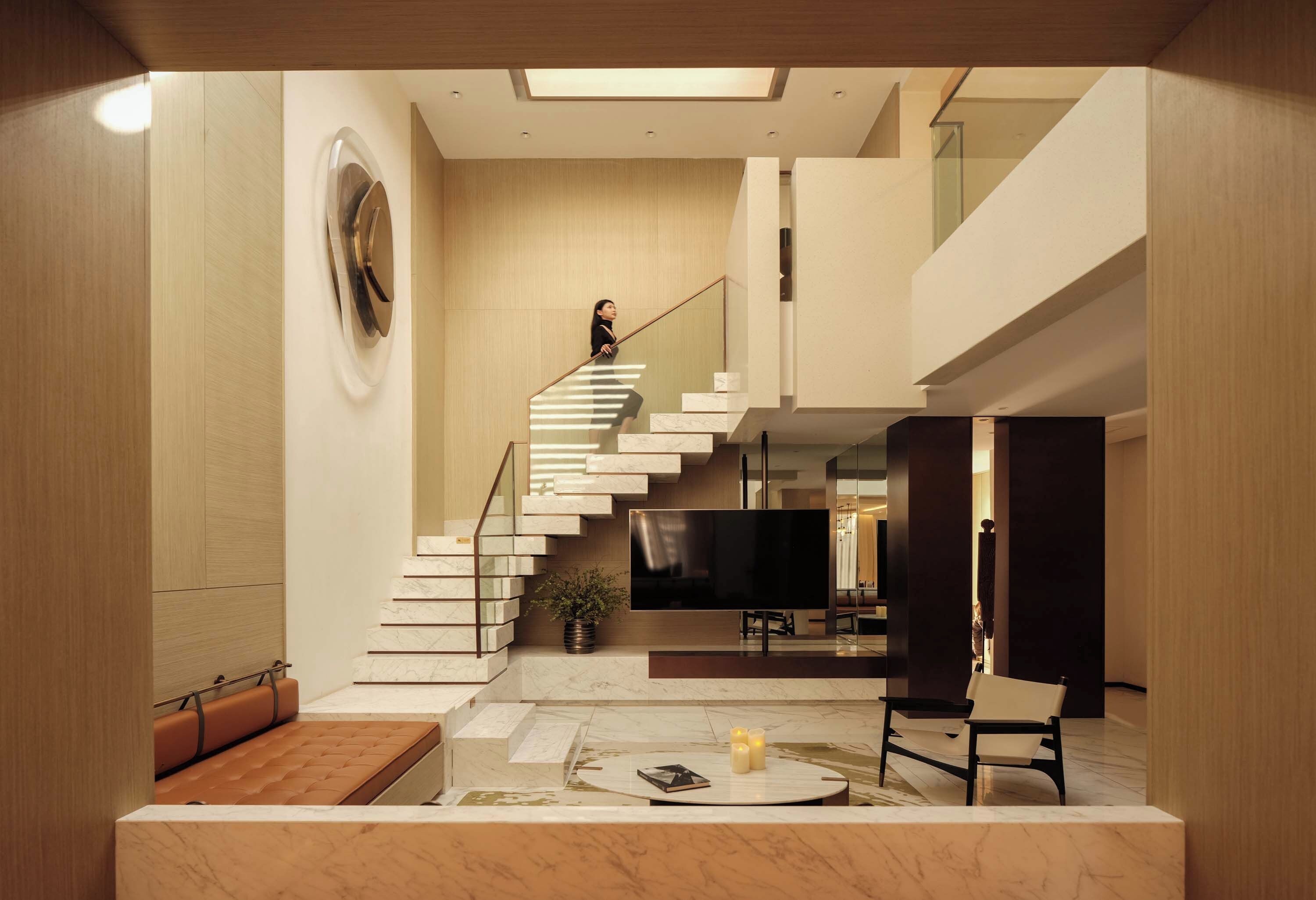A modern interior with a staircase, a flat-screen TV, and a seating area.