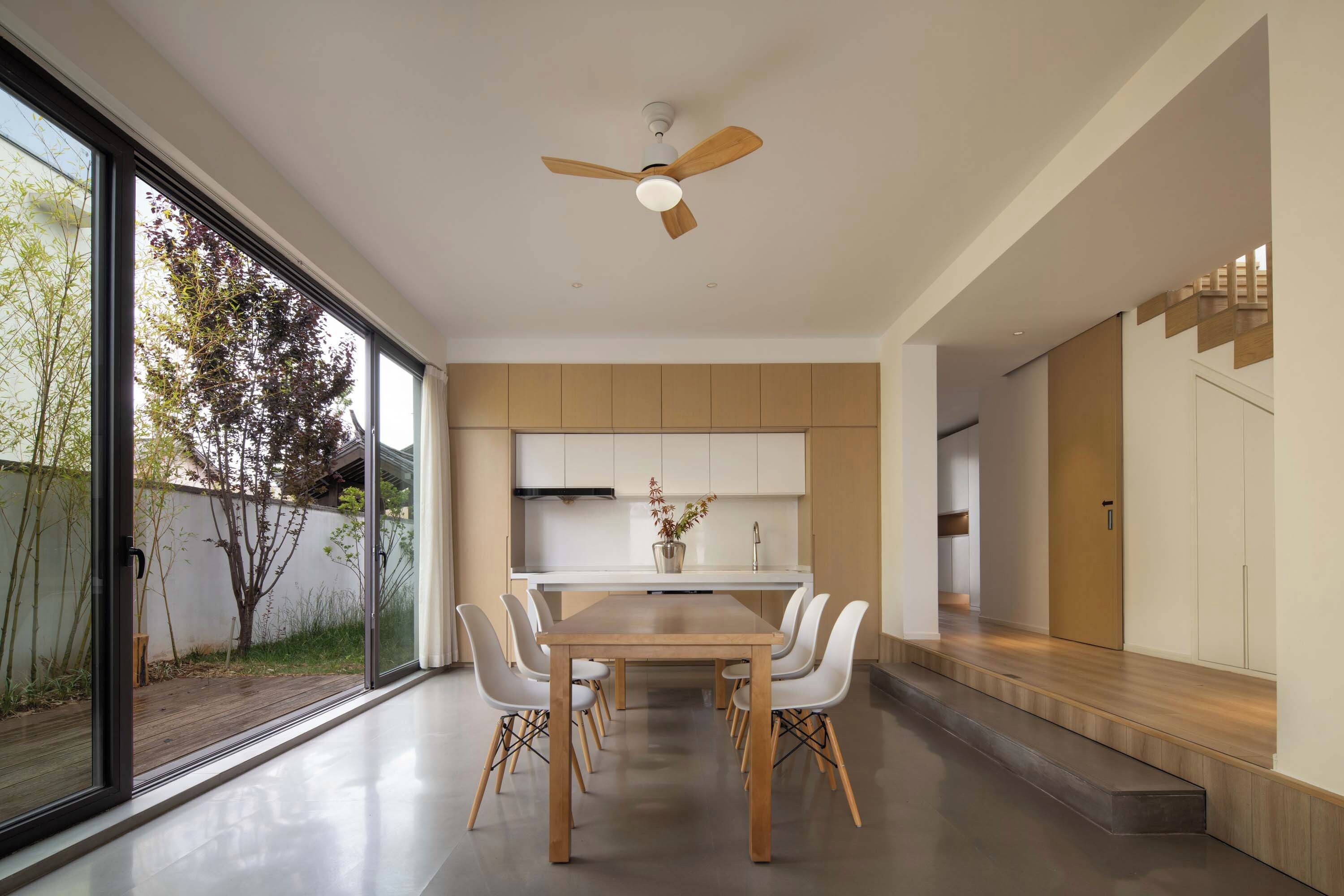Una cocina moderna con comedor, ventanas amplias y un ventilador de techo.