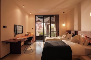 Una habitación de hotel con cama, escritorio, televisor y vistas al exterior.