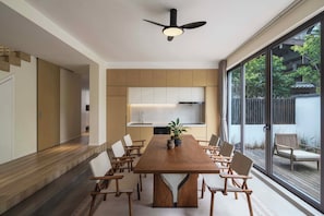 Una cocina moderna con armarios de madera, una isla central y un comedor con mesa y sillas de madera.