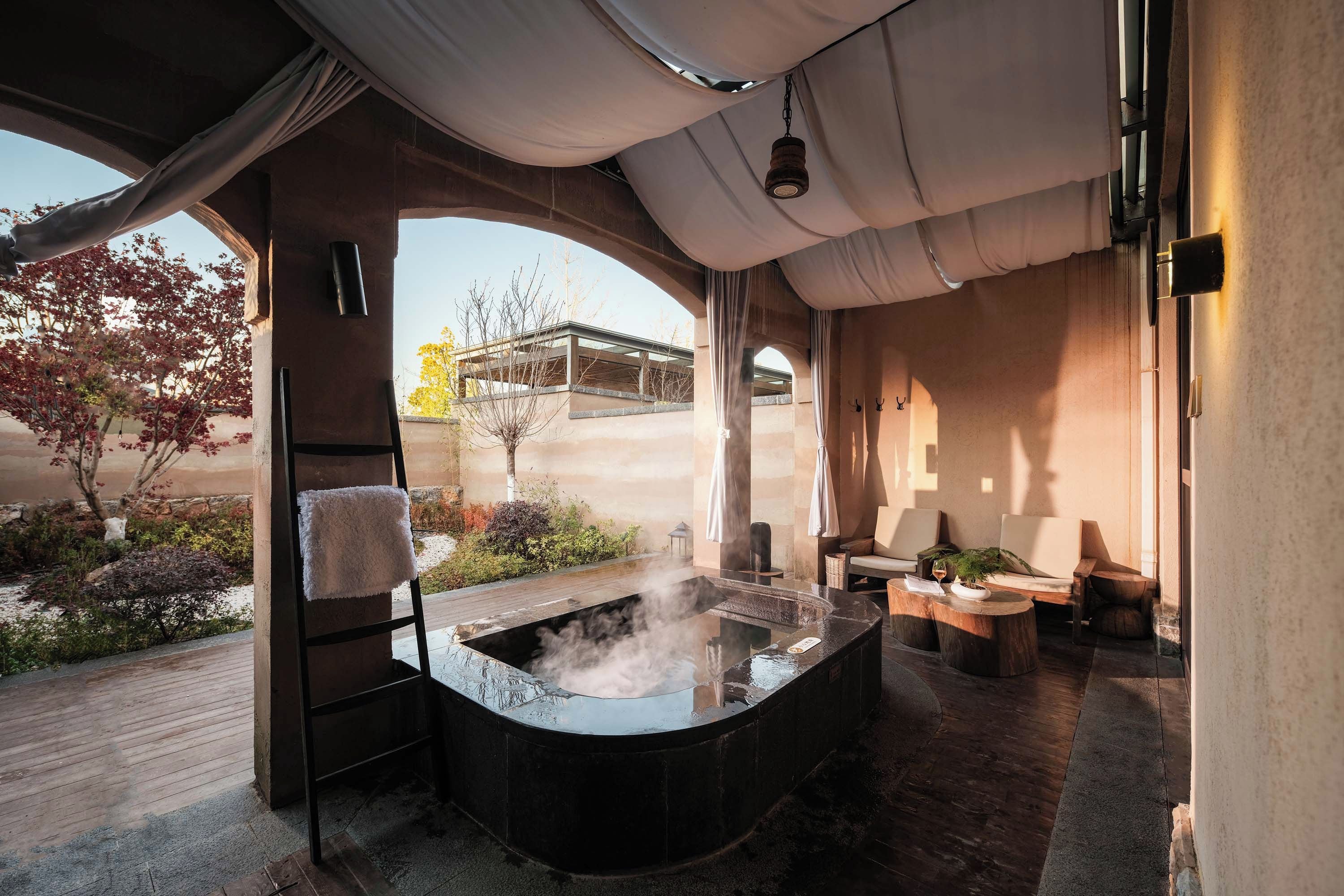 Un área de spa con una bañera de hidromasaje, asientos y vistas al exterior.