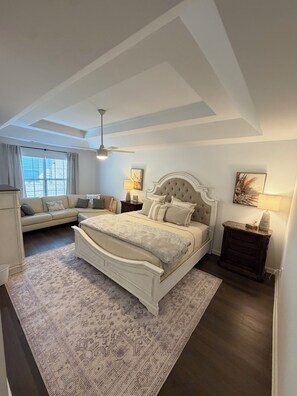 A bedroom with a large bed, a sofa, a nightstand, and a ceiling fan. -  Stylish 3BR Home with Fireplace (Marietta)