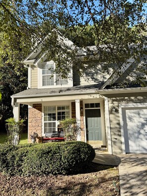 A two-story house with a front porch, a garage, and a well-maintained lawn. -  Stylish 3BR Home with Fireplace (Marietta)