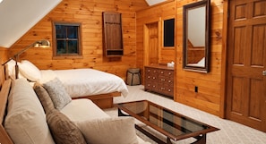 A cozy bedroom with a bed, a sofa, a dresser, and a mirror.