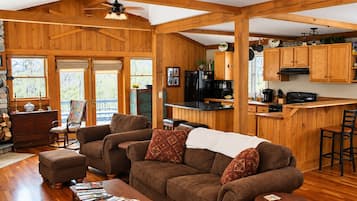 A cozy cabin interior with a living room, kitchen, and dining area.