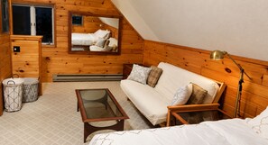 Une pièce chaleureuse avec un décor intérieur en bois, un canapé, une table à plateau en verre et une lampe.