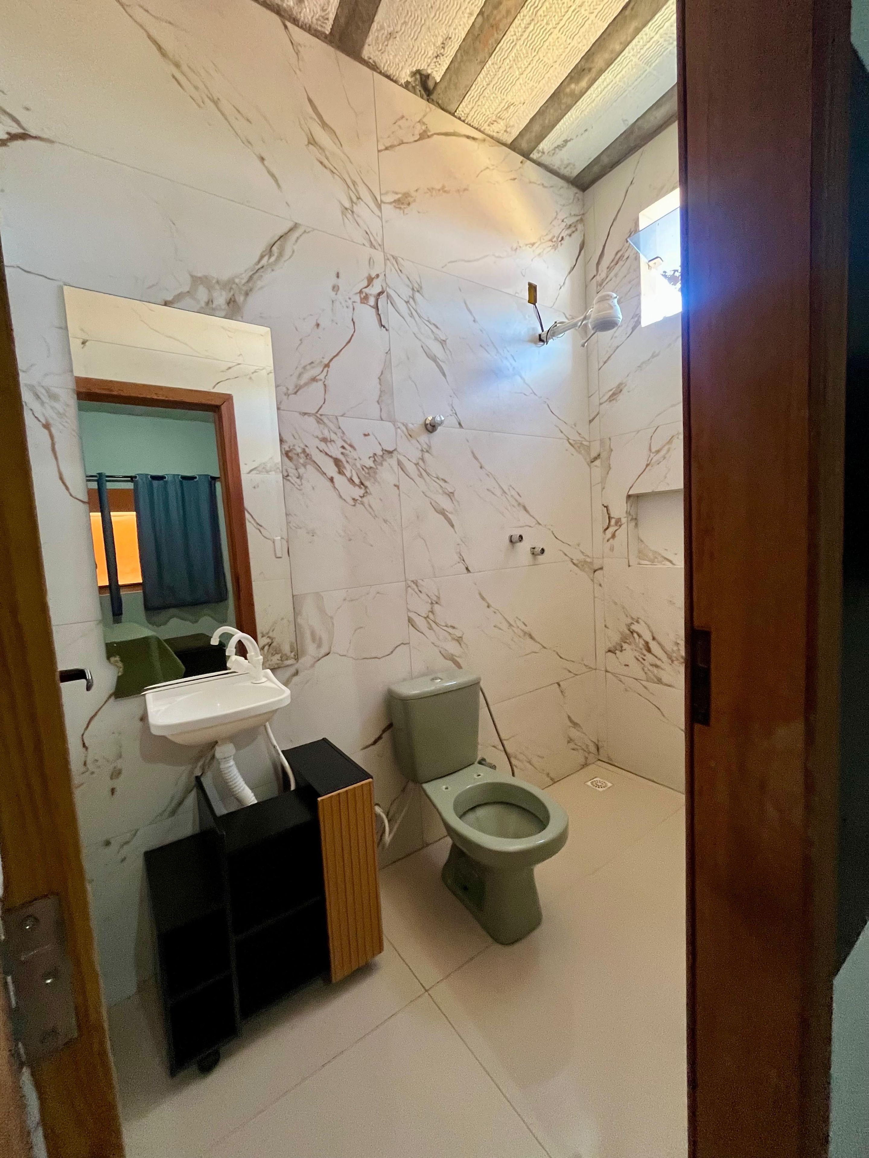 Casa de banho com chão de mármore, lavatório, sanita e espelho.