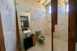 A bathroom with a marble wall, a sink, a toilet, and a cabinet. - Urban Hospedagem Almenara (Almenara)