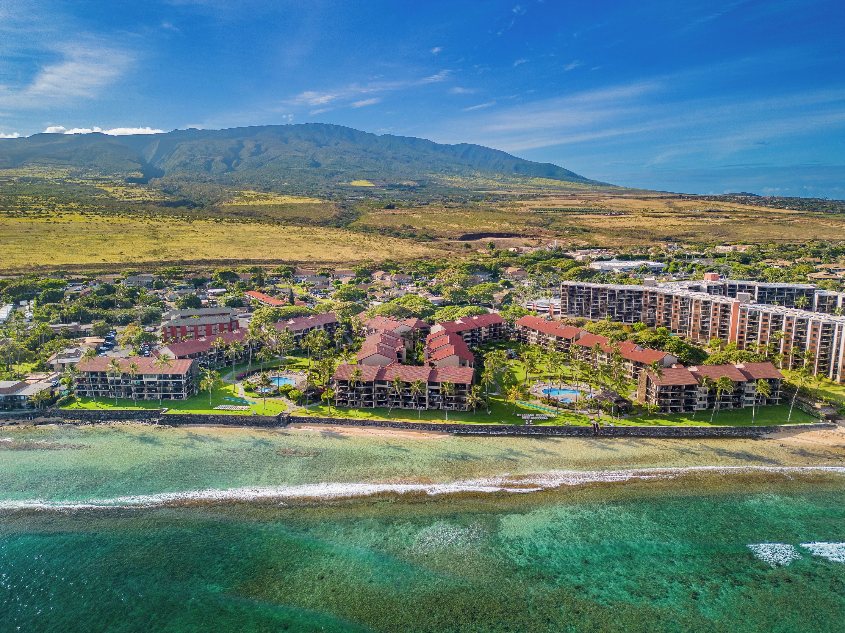 An aerial view of a resort with multiple buildings, a beach, and clear turquoise waters.