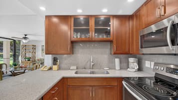 A modern kitchen with wooden cabinets, a stainless steel microwave, a built-in oven, and a granite countertop.