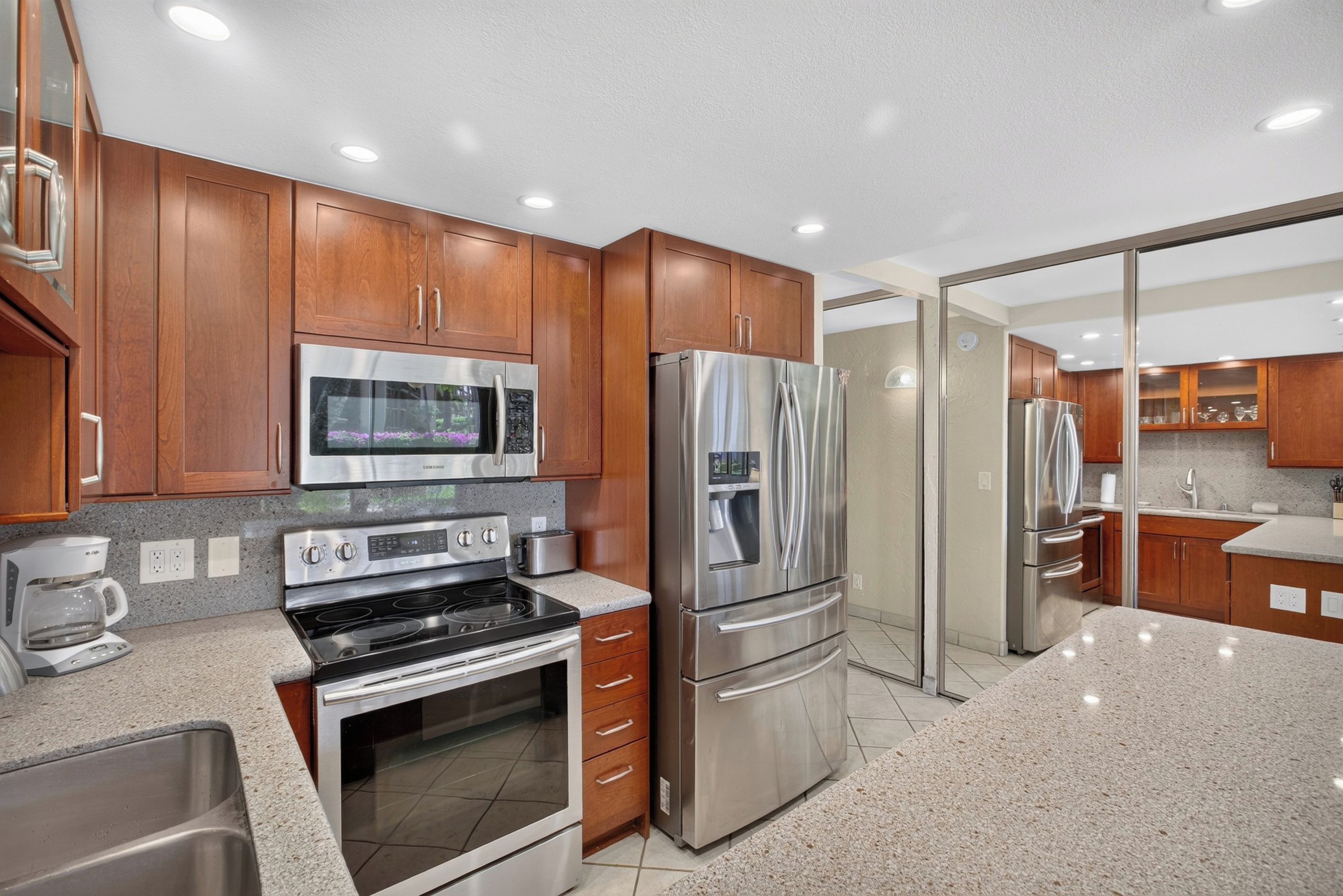 A modern kitchen with stainless steel appliances, wooden cabinets, and a granite countertop.