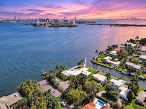 A coastal residential area with houses, a marina, and a city skyline in the background. - Bayfront 6BR Compound | Pool, Hot Tub & Views (Miami)
