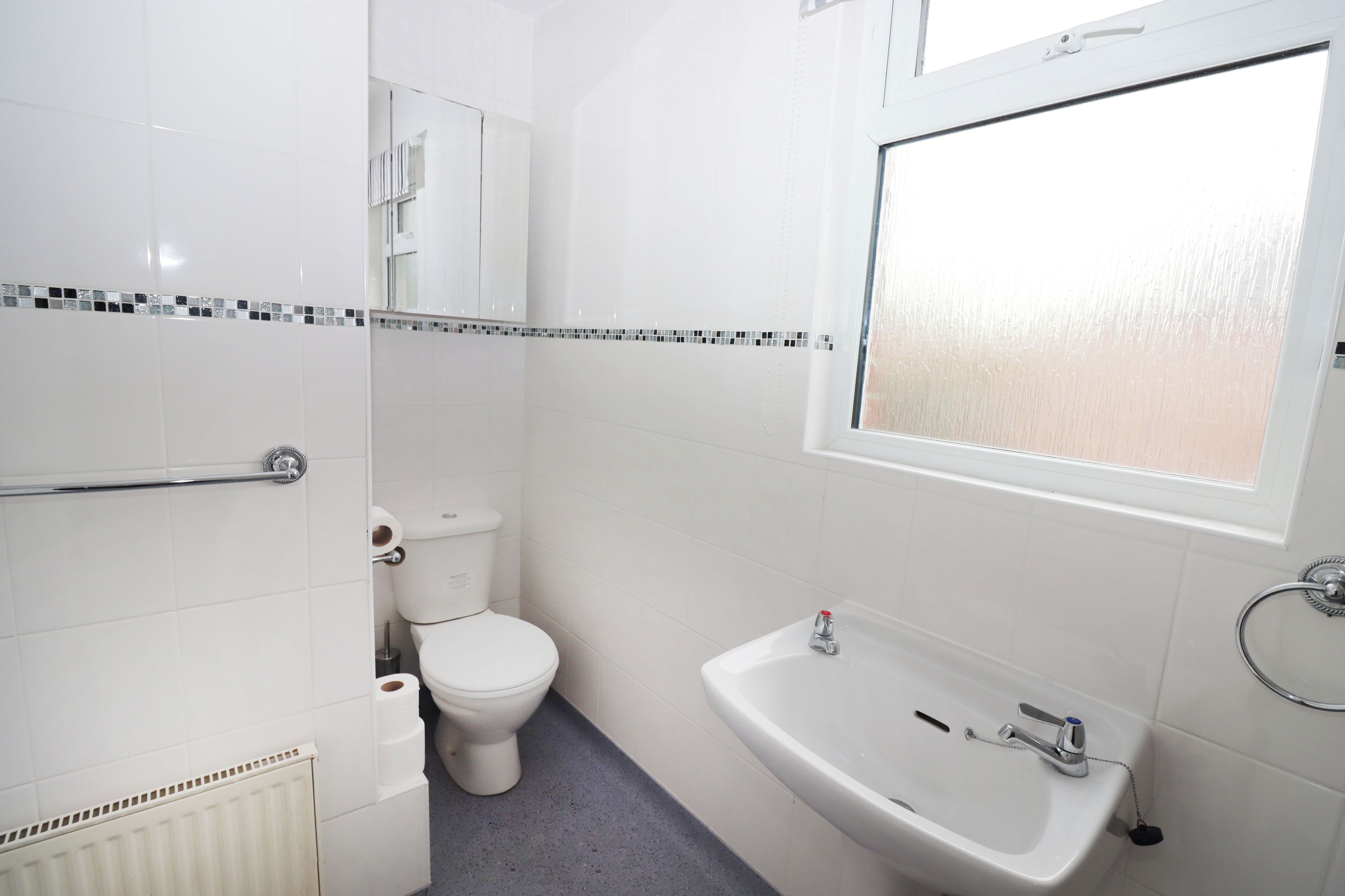 A bathroom with a toilet, a sink, and a window.