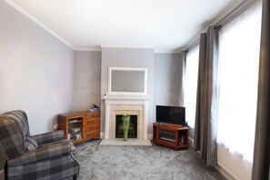 Ein Wohnzimmer mit Kamin, Fernseher und Sofa.