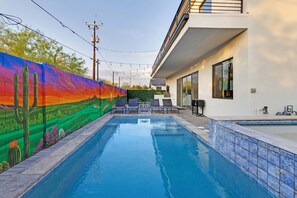 A swimming pool with a mural on the adjacent wall, outdoor seating, and a modern building with large windows. - Heated Pool & Spa, Golf Simulator, Billiards - Walking Distance to Old Town (Scottsdale)