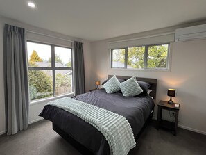 Une chambre à coucher avec un grand lit, deux tables de chevet et une fenêtre avec des rideaux.
