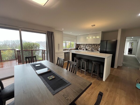 A modern kitchen with a central island, wooden flooring, and a dining area with a long table and chairs.