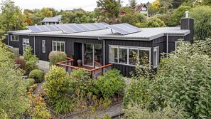 A modern house with solar panels, large windows, and a wooden deck.