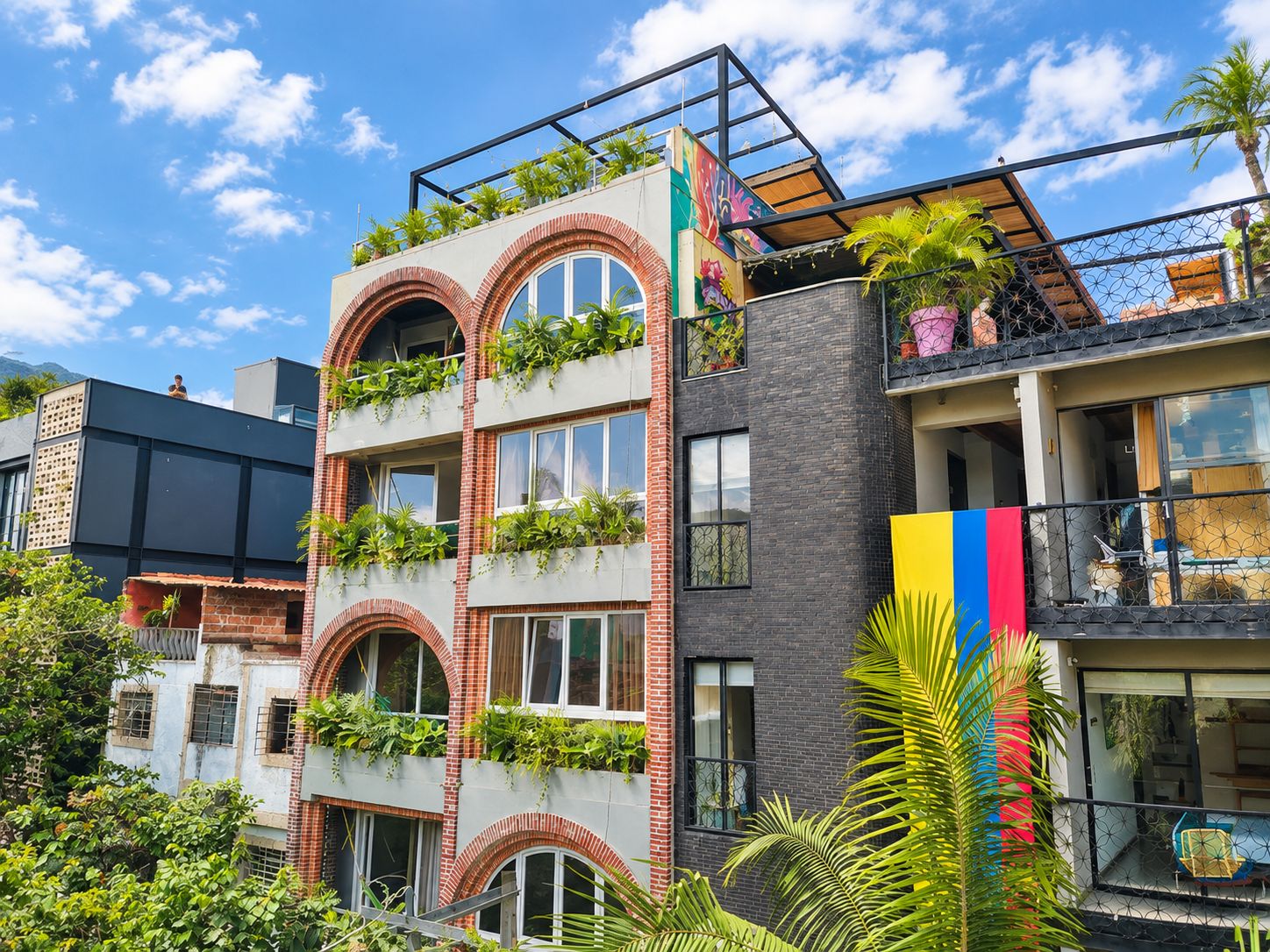 Un edificio de varios pisos con balcones, ventanas arqueadas y una combinación de ladrillo y materiales de fachada oscura.