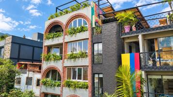Un edificio de varios pisos con balcones, ventanas arqueadas y una combinación de ladrillo y materiales de fachada oscura.