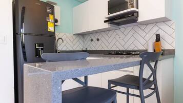 Una cocina compacta equipada con refrigerador, microondas y estufa a gas.