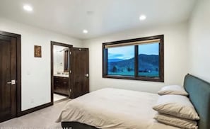 Ein Schlafzimmer mit einem Bett, einem Fenster mit Blick und einer Tür zu einem Badezimmer.