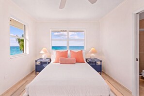 A restful bedroom with coral accents, crisp linens, and Caribbean views, with room-darkening blinds for a peaceful night’s sleep. - New Re-Furnished 2bd Condo with Ocean Views from Every Room on Seven Mile Beach (George Town)