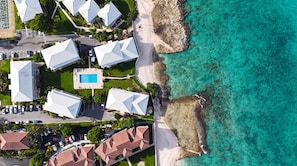Vista aérea de um hotel à beira-mar, com vários edifícios, piscina e praia.