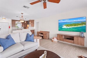 A modern living room with a sofa, coffee table, and a flat-screen TV mounted on the wall. - New Re-Furnished 2bd Condo with Ocean Views from Every Room on Seven Mile Beach (George Town)