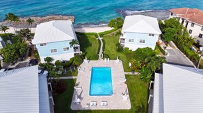 A resort with a central swimming pool, beachfront villas, and a well-maintained lawn. - New Re-Furnished 2bd Condo with Ocean Views from Every Room on Seven Mile Beach (George Town)