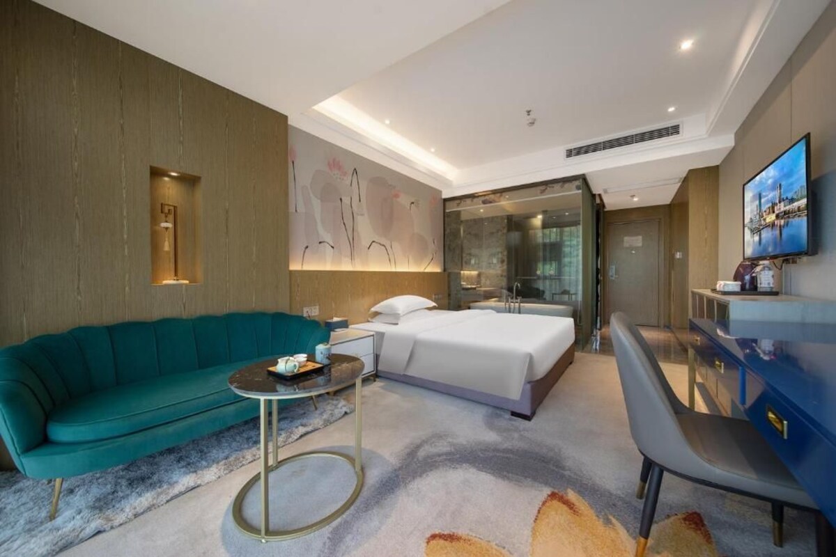 Ein modernes Hotelzimmer mit einer Couch, einem Bett, einem Schreibtisch und einem Fernseher.
