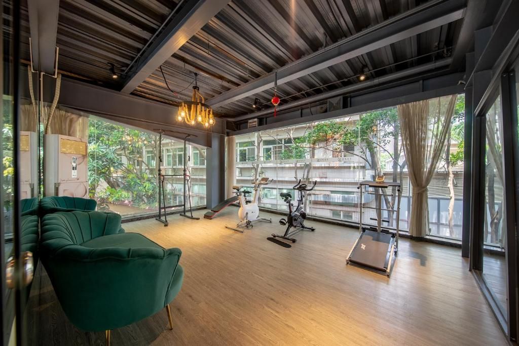 Un gimnasio moderno con equipo de ejercicio, ventanas amplias y un sofá verde.