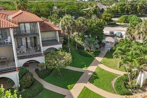 A two-story building with a balcony, surrounded by well-maintained gardens and palm trees.