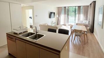 A modern kitchen with a central island, a dining area with a table and chairs, and a living space with a sofa and a TV.