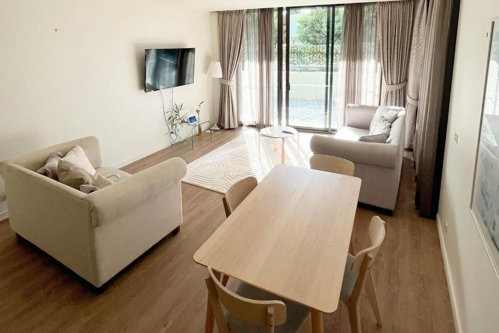 A living room with a sofa, a table, and a TV mounted on the wall.