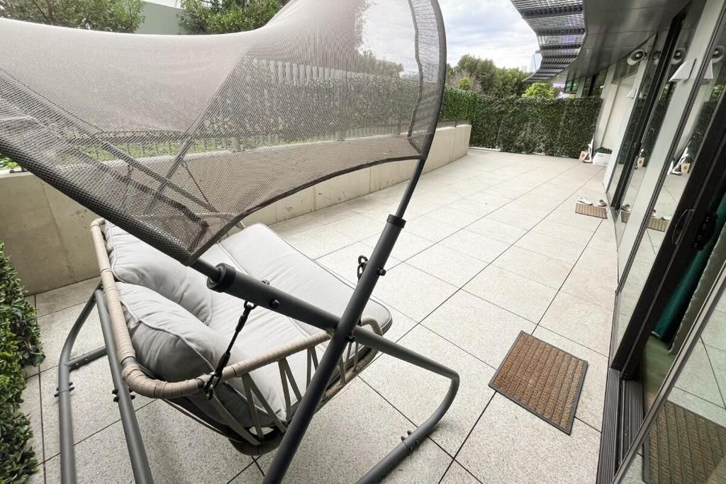 A covered outdoor seating area with a mesh canopy, a cushioned chair, and a tiled patio.