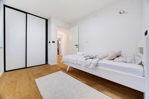 A modern bedroom with a bed, a white rug, and a wooden floor. - Green Zone Apartment With Terrace And Parking, Zagreb, Croatia (Zagreb)