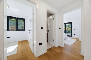 A modern interior with white walls, wooden flooring, and a view through a window. - Green Zone Apartment With Terrace And Parking, Zagreb, Croatia (Zagreb)
