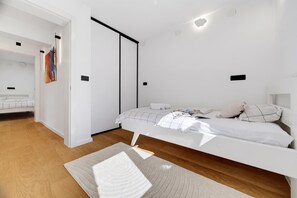 A modern bedroom with a bed, a bedside table, a nightstand, and a wall-mounted light fixture. - Green Zone Apartment With Terrace And Parking, Zagreb, Croatia (Zagreb)